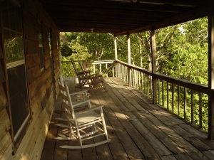 Rocking chairs welcome guests to the front porch of a rustic log cabin